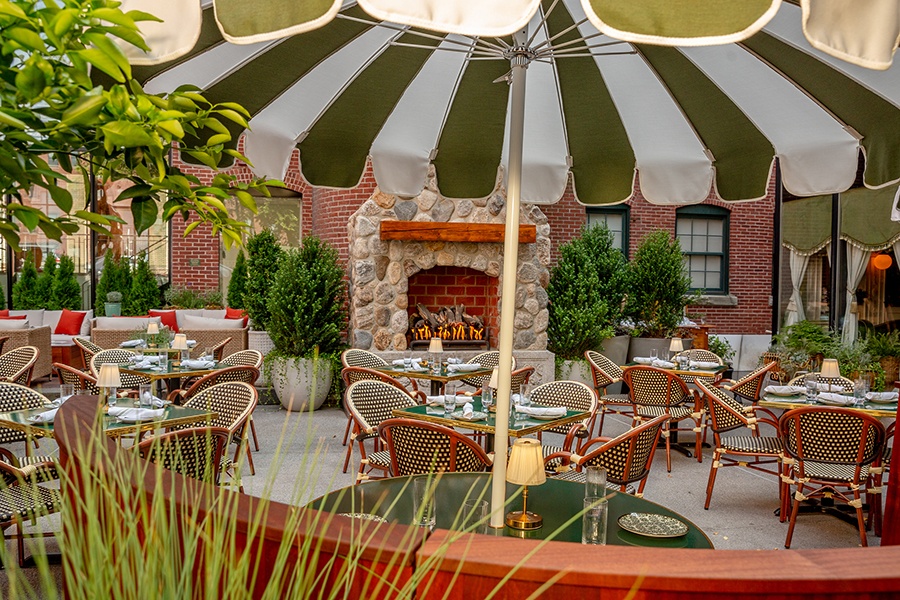 An Italian-inspired large restaurant patio with green-and-white-striped umbrellas and a fireplace.