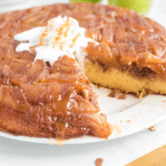 caramel apple upside down cake on a white plate with a scoop of whipped cream on top
