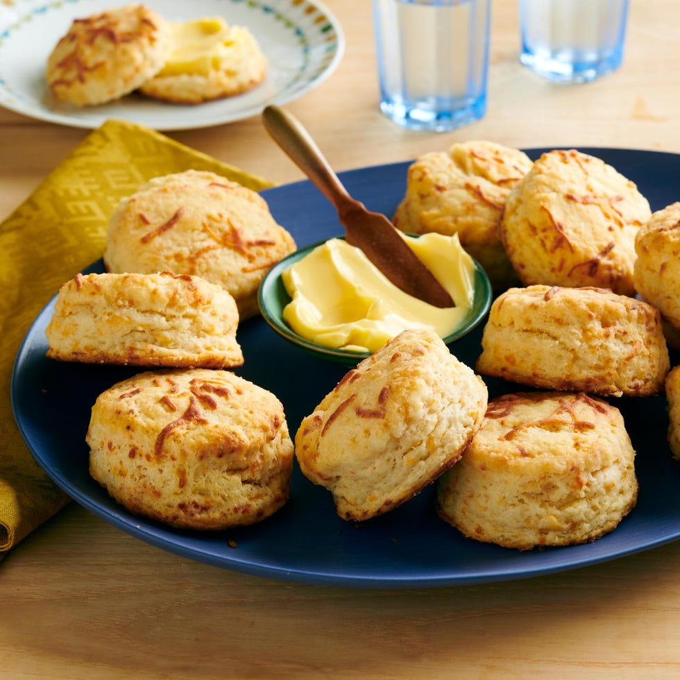 plate of freshly baked biscuits with a bowl of butter and a spreading knife