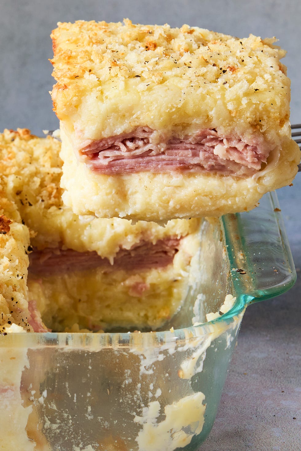 mashed potatoes layered with cheese and ham baked in a casserole dish