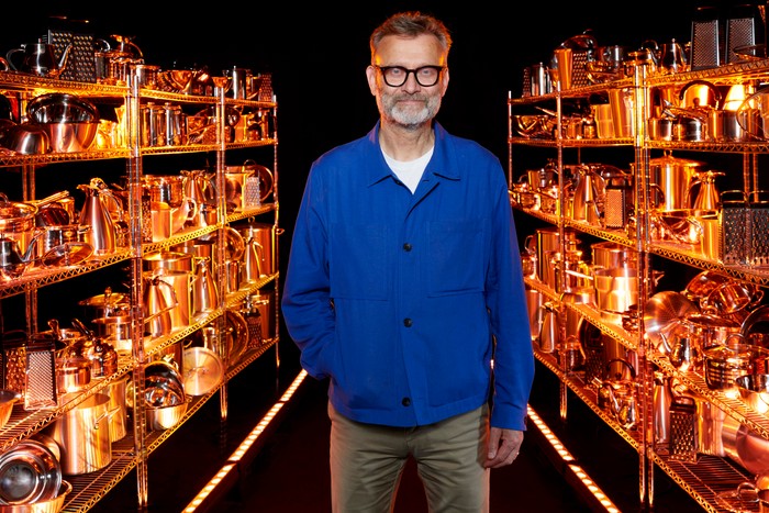 Hugh Dennis smiling ahead, wearing a dark blue shirt and khaki trousers.