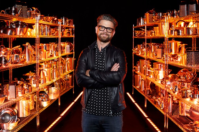 Jack Osbourne smiling ahead with his hands folded in front of his chest.