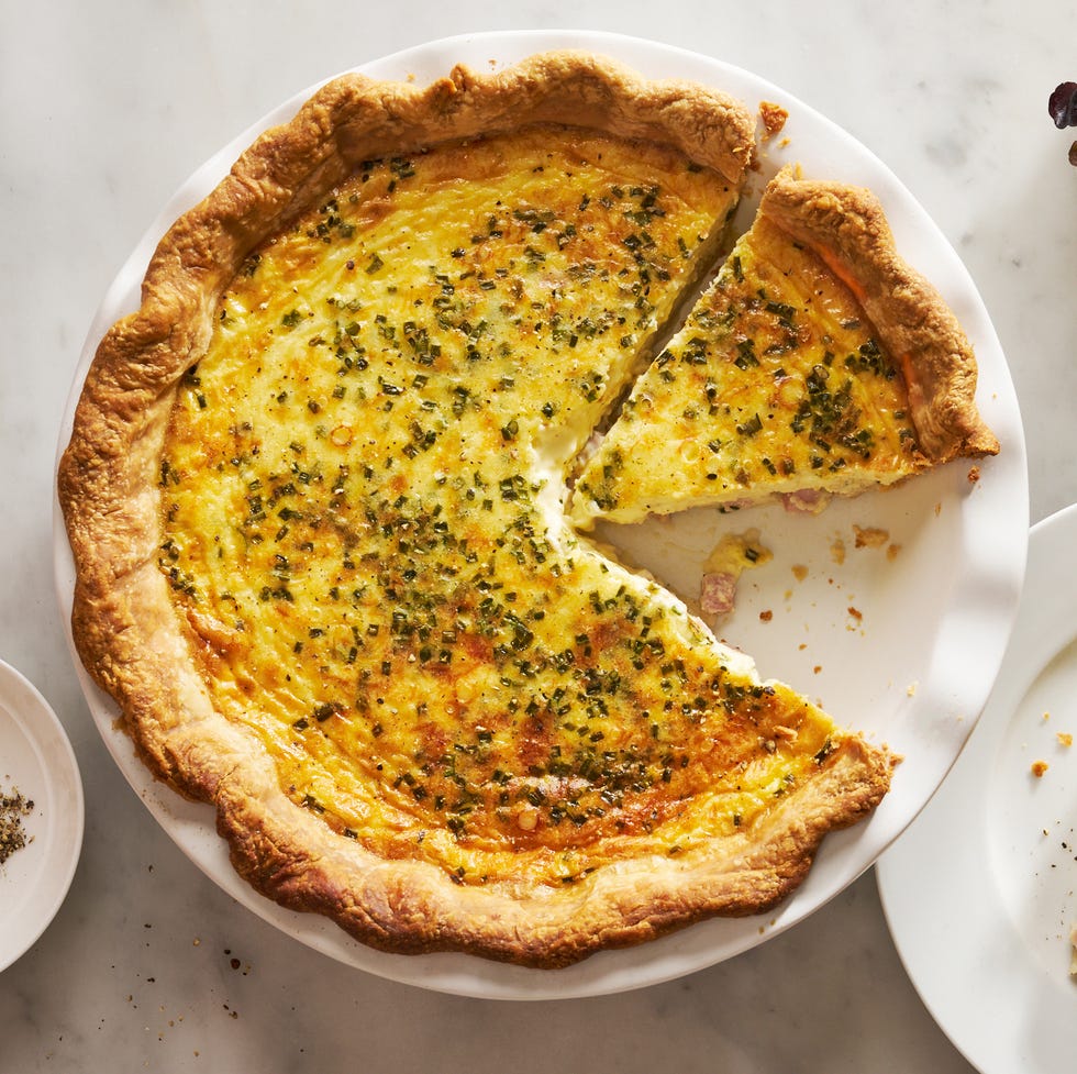 ham and cheese quiche beside a plate with a slice of quiche and a salad bowl