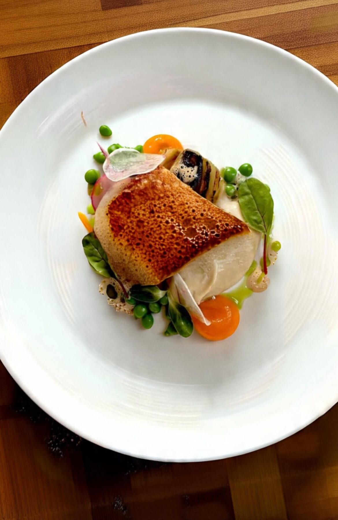 Seared Seabass. Carrot coulis. Charred veg. Green peas and micro greens. No foam.