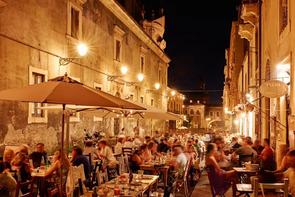 Italy, Sicily, Catania, people dining and socialising outside at night