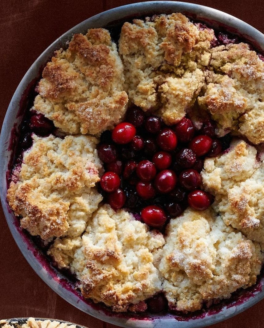 cranberry cherry cobbler pie in a metal pie tin with cobbler topping around the edges and an open space in the center revealing the cranberries and cherries