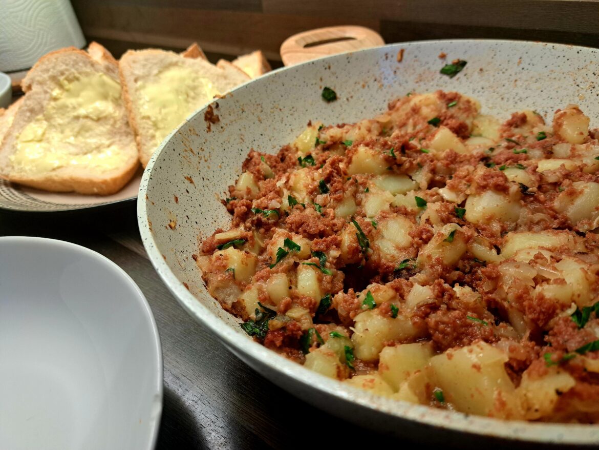 Simple corned beef hash served with thick buttered bread, salad and Branston beans