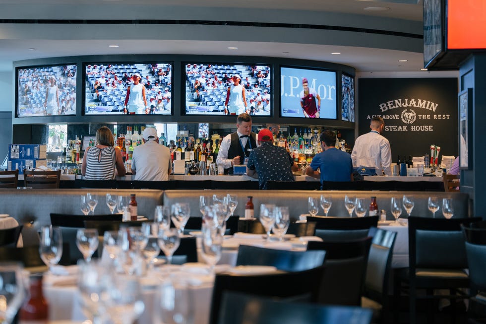 A lively restaurant bar with patrons enjoying drinks and sports on multiple screens.