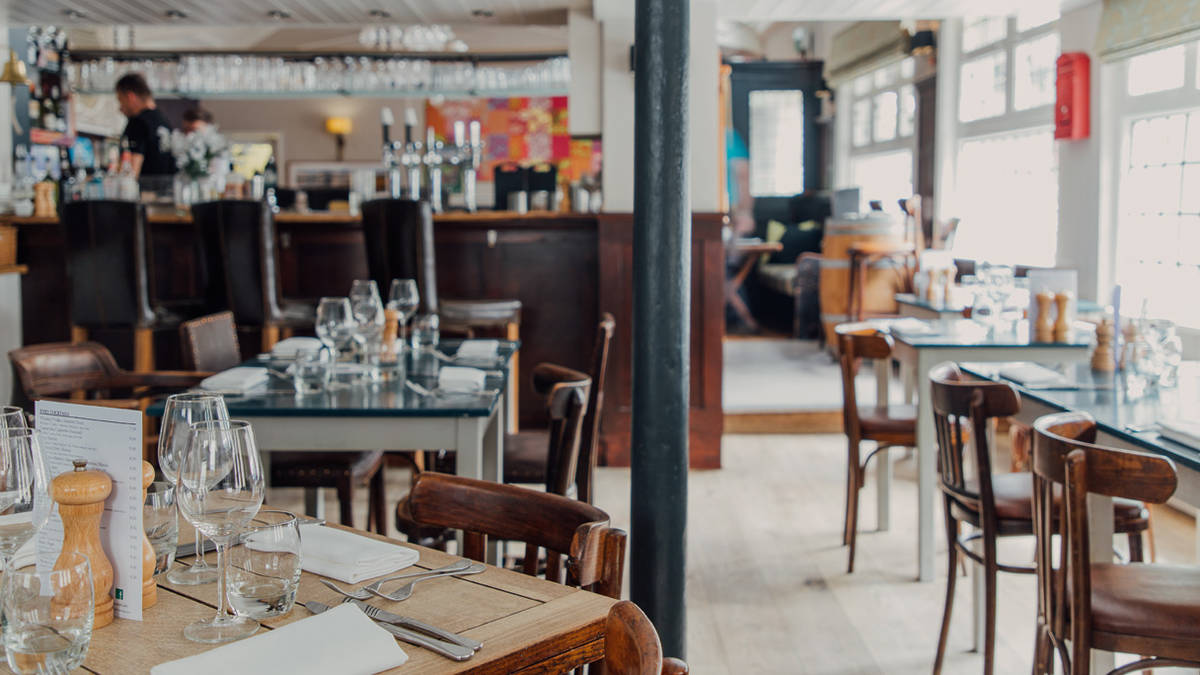 the interior of the fox and grape pub in wimbledon showing tables and chairs in a restaurant-esque area near a bar, in a room full of light