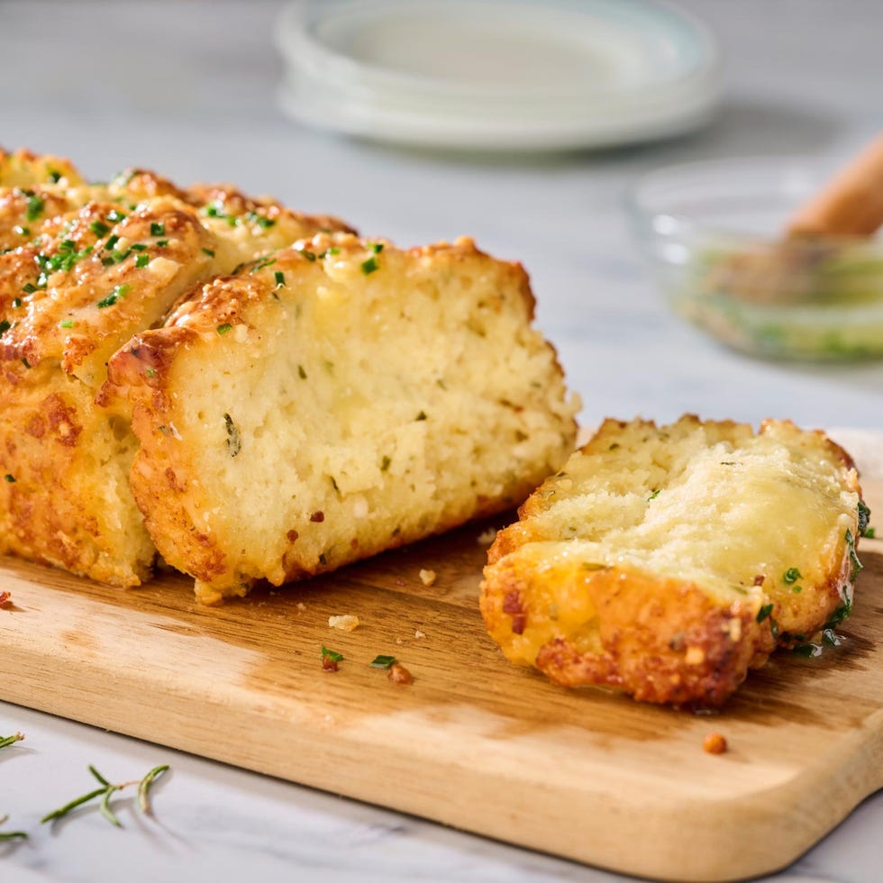 freshly baked bread loaf sliced and garnished with herbs on a cutting board