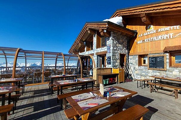 An image of a ski resort restaurant and terrace with mountains in the background in La Plagne Paradiski