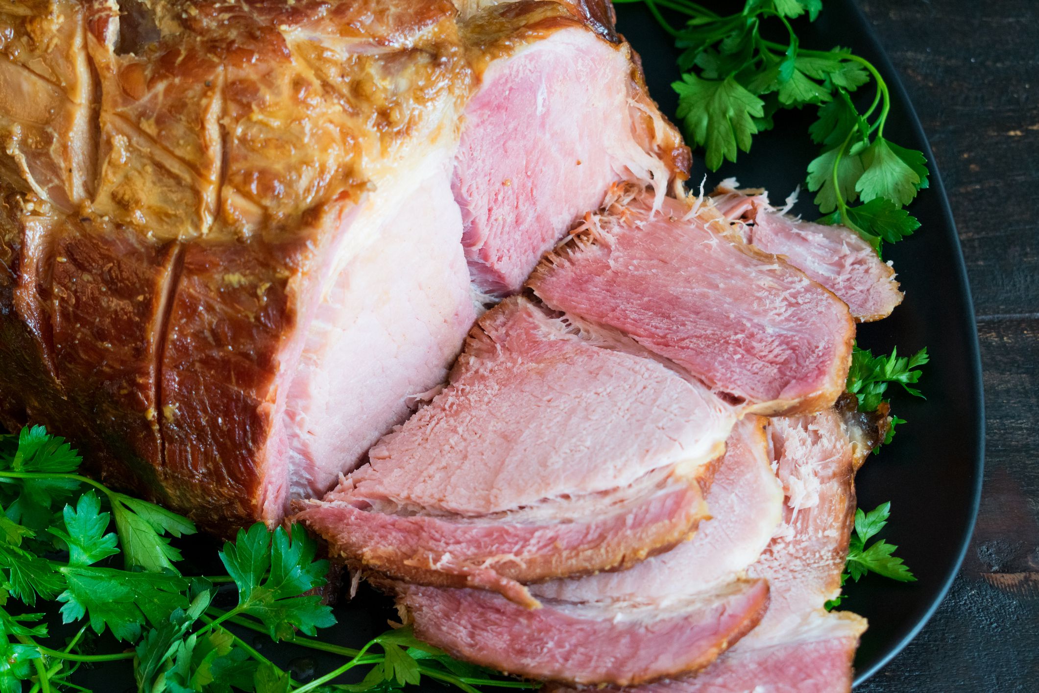 Sliced of glazed Christmas ham served on a garnished platter