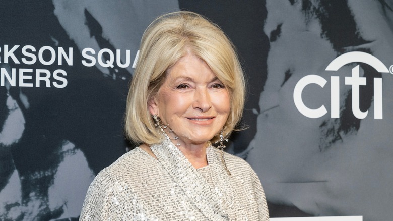 Smiling Martha Stewart wearing a sparkly ivory top in front of a promotional background