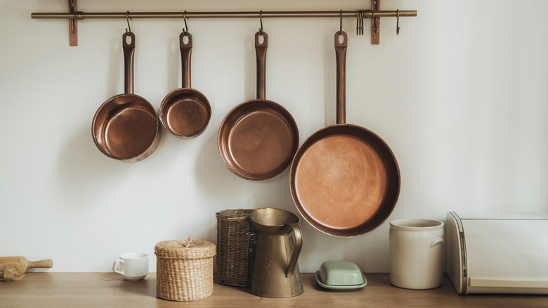 Collection of antique copper stew pans hanging on rack