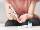 A woman uses a lancet on her finger to check blood sugar level by glucose meter.