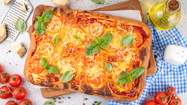 Rectangular pizza with tomoatos, olive oil, and checked napkin