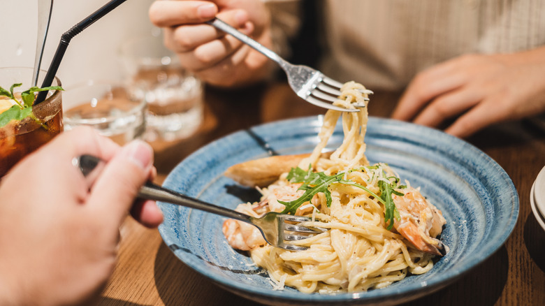 A couple sharing spaghetti at a restaurant