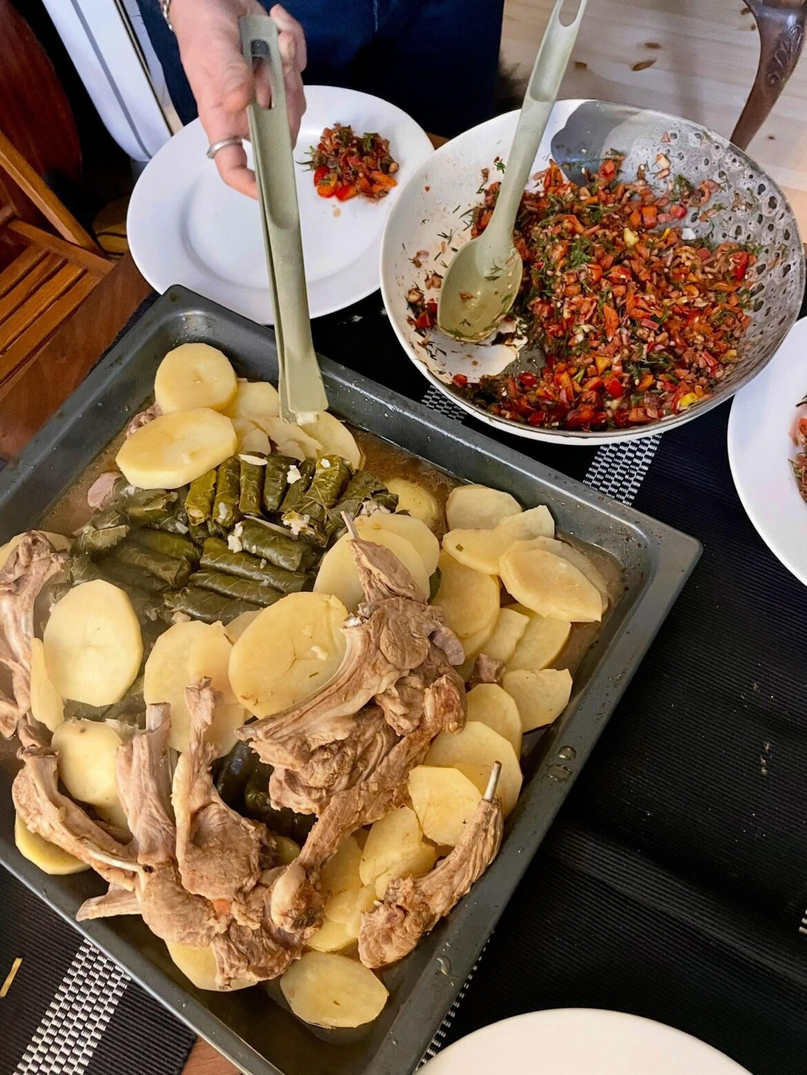 Homemade stuffed grape leaves, lamb, and potatoes with salad