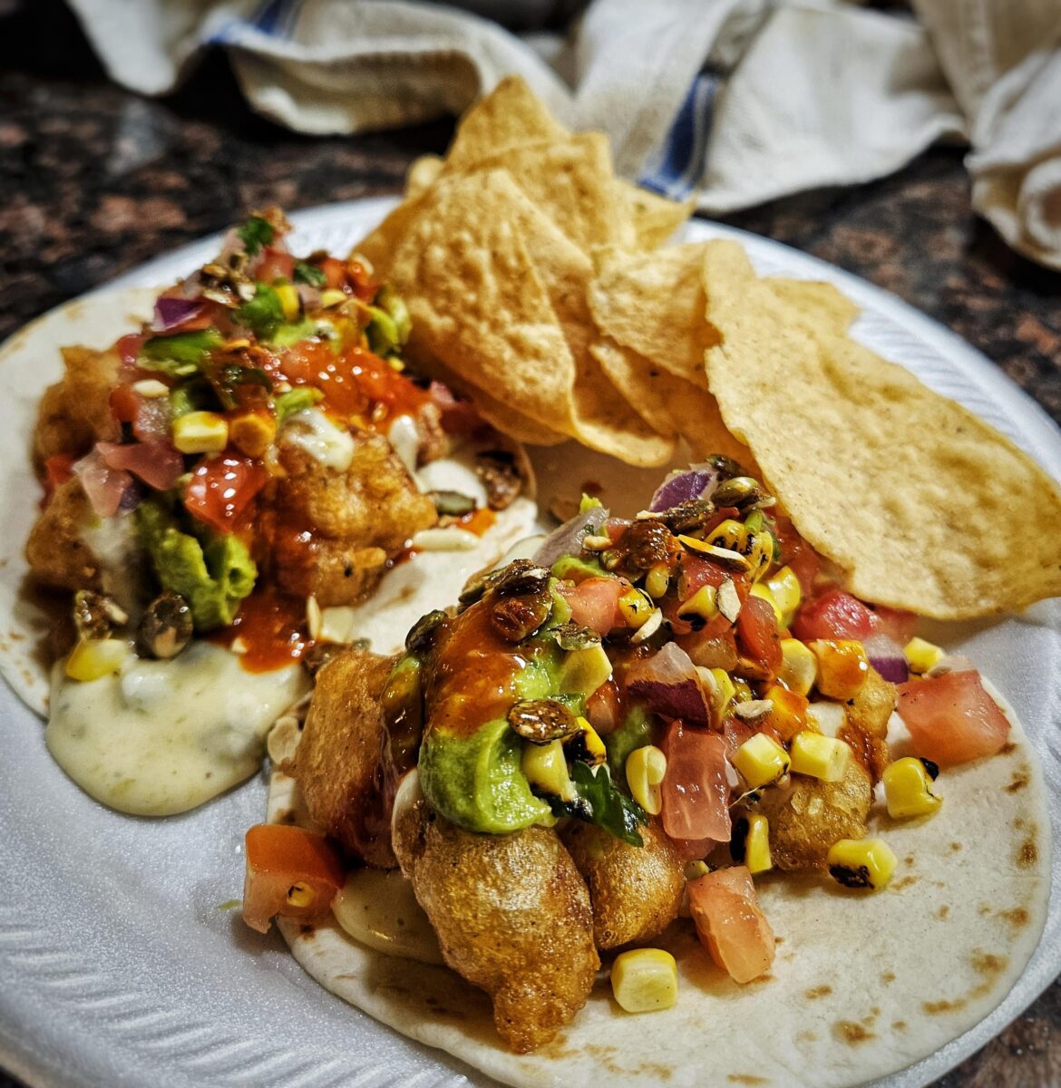 Beer-battered cauliflower tacos with green chile queso blanco, avocado, roasted corn pico de gallo, and candied pepitas.