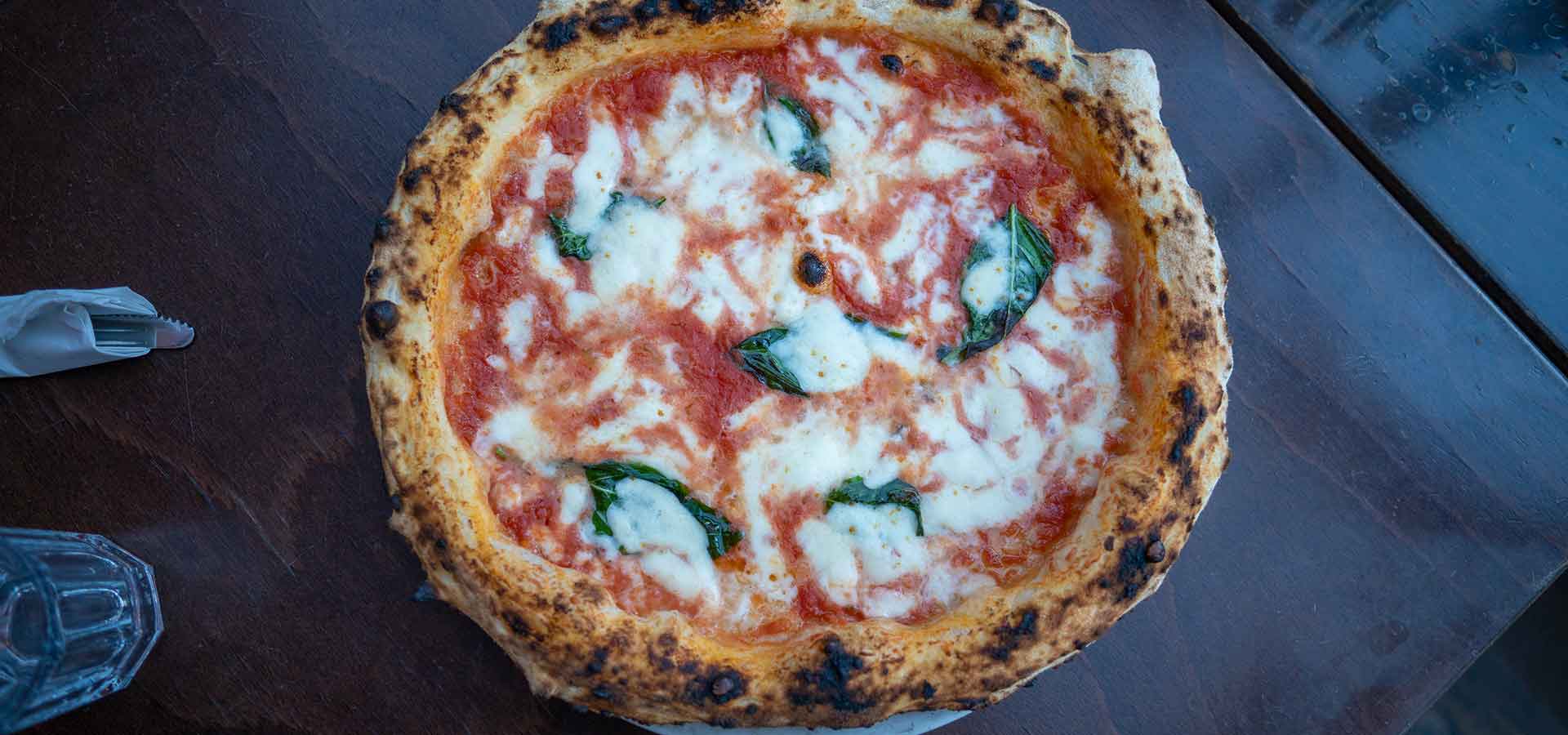 A pizza with red saucce, green basil, and white cheese. 
