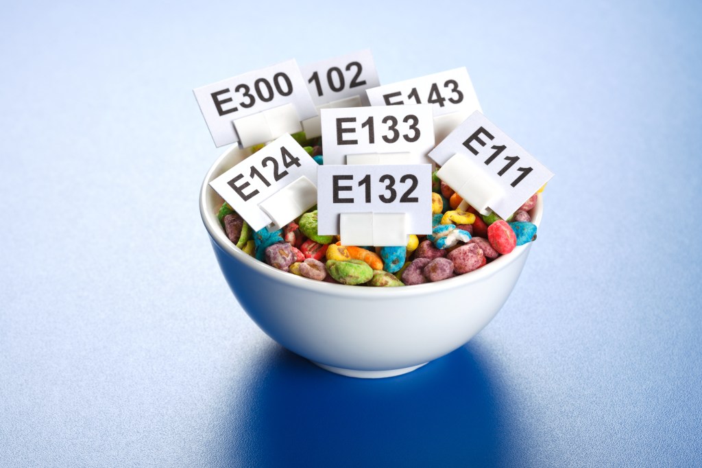 Bowl of colorful cereal with food additive E-numbers.