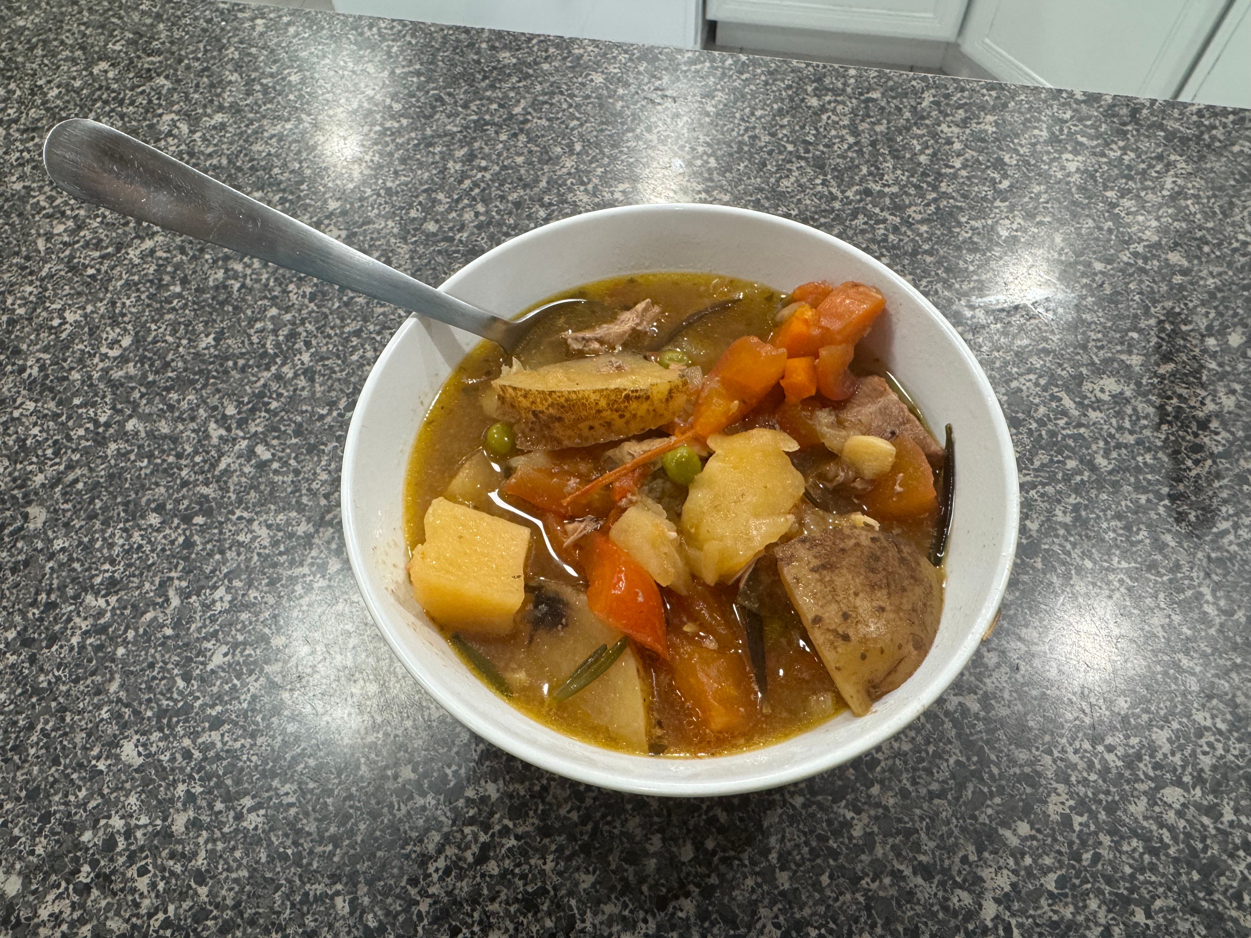 A bowl of pork spezzatino sits on a table.