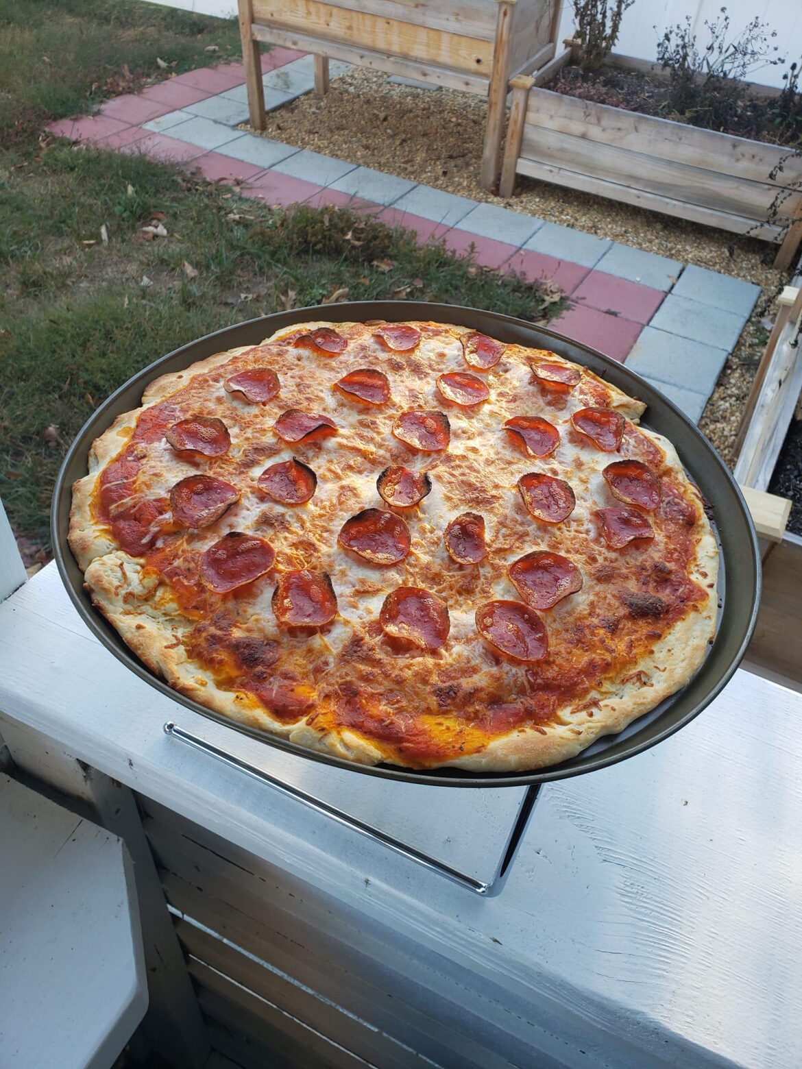 Pepperoni pizza with homemade dough and sauce cooked in outdoor pizza oven.