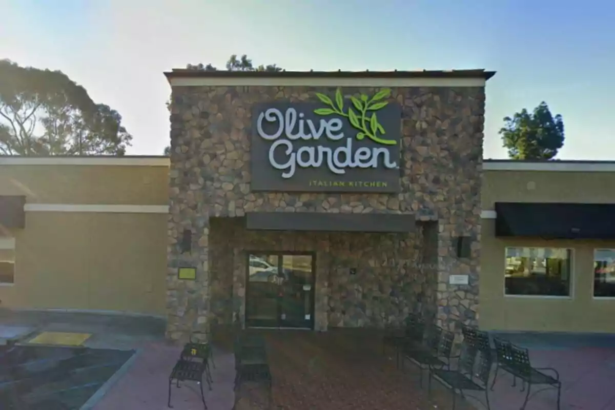 Facade of an Olive Garden restaurant with stone walls and metal benches at the entrance