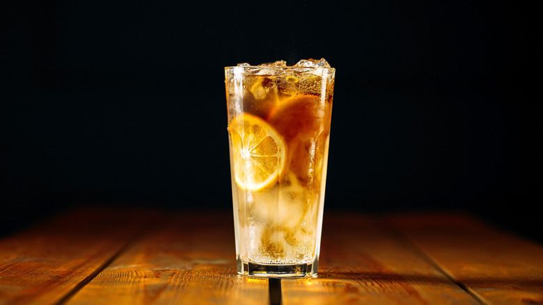 Glass of Long Island iced tea on wooden surface