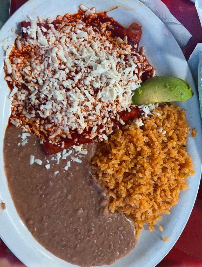 Red enchiladas with beans and rice.