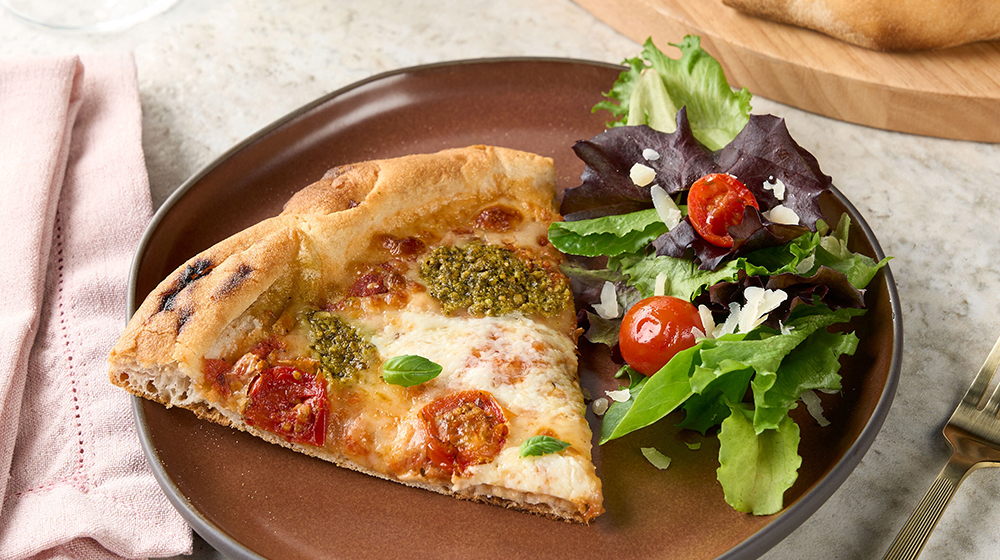 Discover Our New Artisan Pizza A slice of Sam's Club artisan pizza on a plate with a salad.