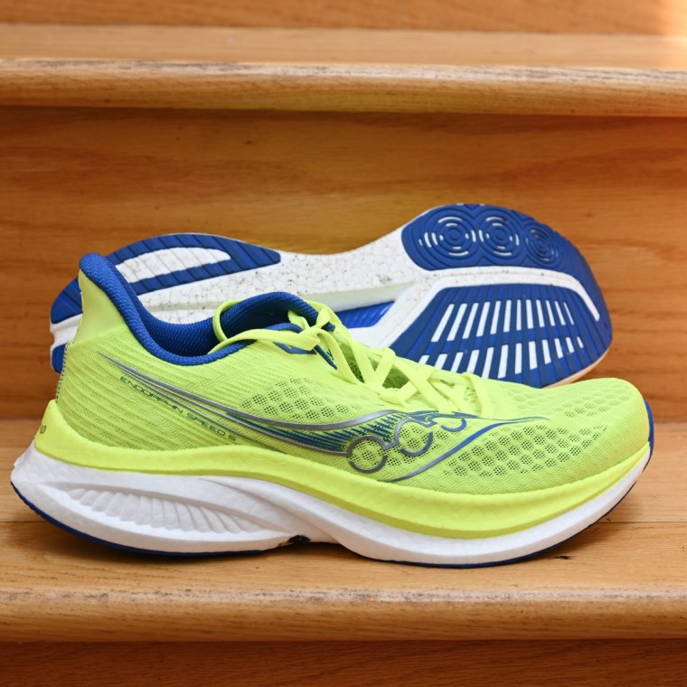 A close up shot of the Saucony Endorphin Speed 5 in a bright yellow green colorway, placed on a wooden staircase.