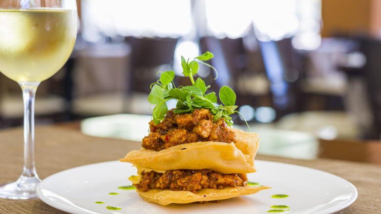 Glass of white wine next to pile of tacos