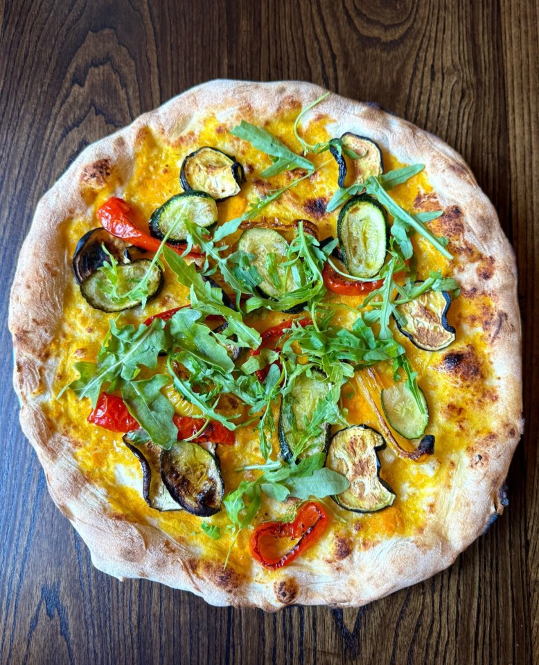 Vegetarian pizza with roasted vegetables and arugula.
