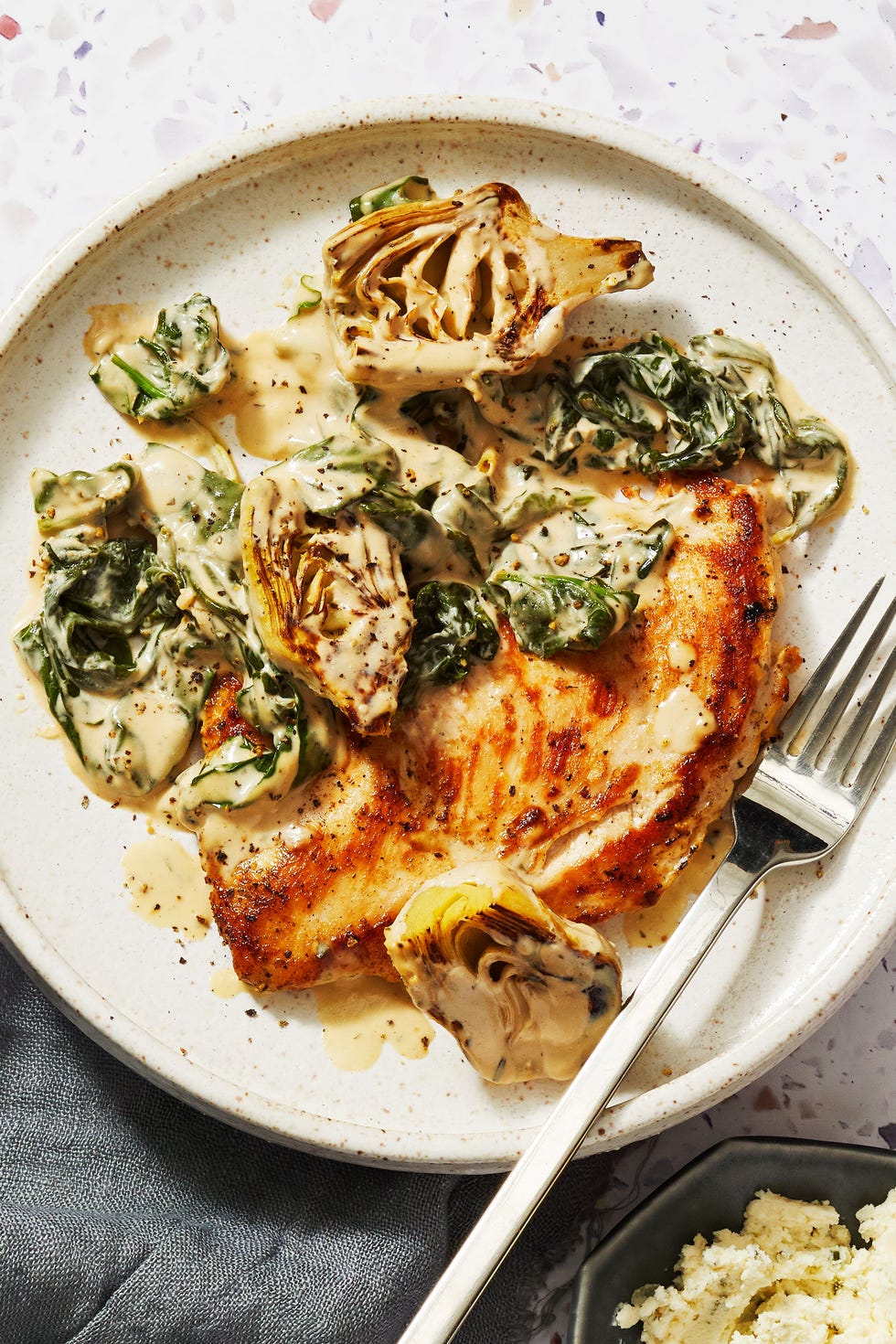 spinach artichoke chicken on a white plate