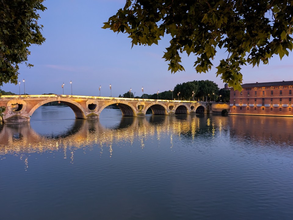 Illuminated bridge over a river at twilight.