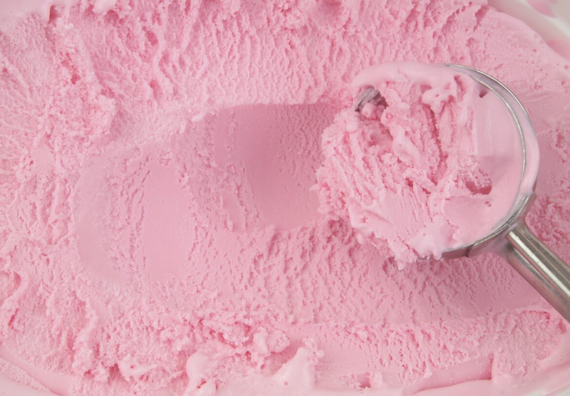 Metallic ice-cream scoop with strawberry ice cream close up