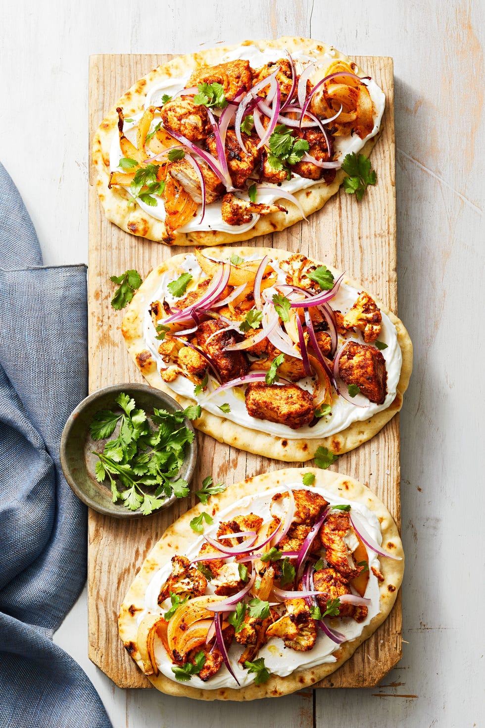 tandoori spiced cauliflower chicken flatbreads on a wooden plank