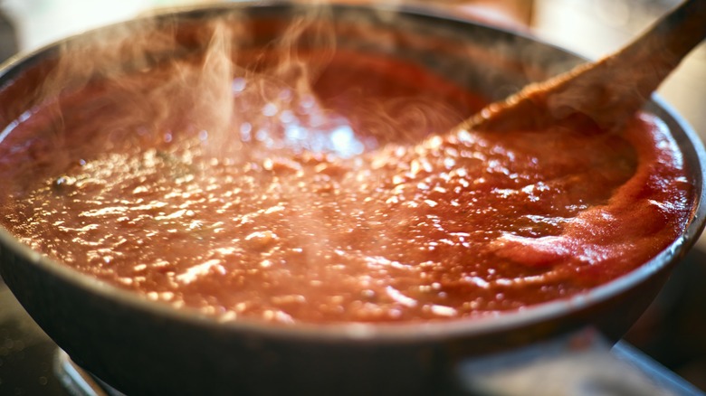 A pan full of steaming hot marinara sauce.
