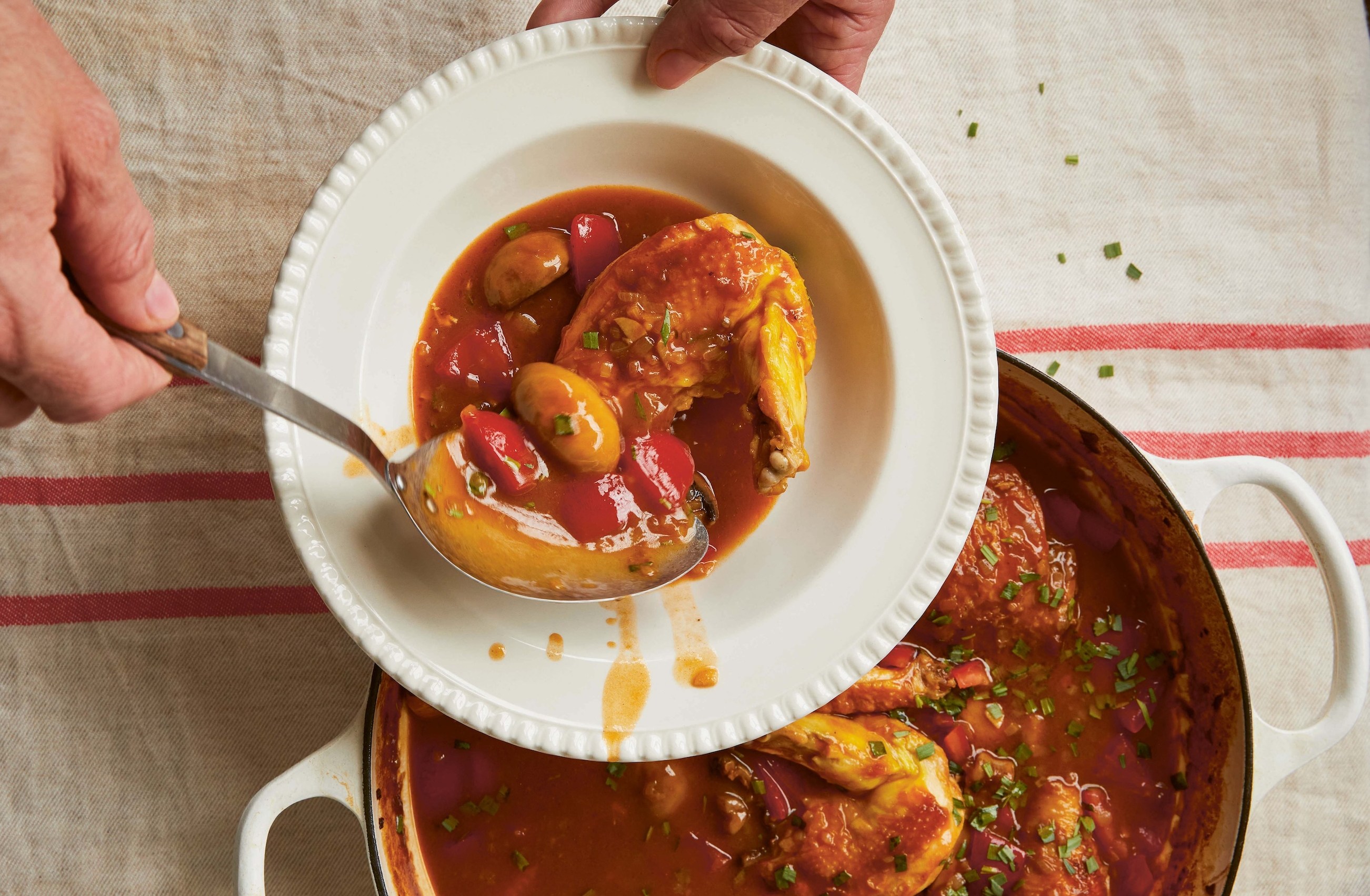Chicken stew being served from a pot into a bowl.