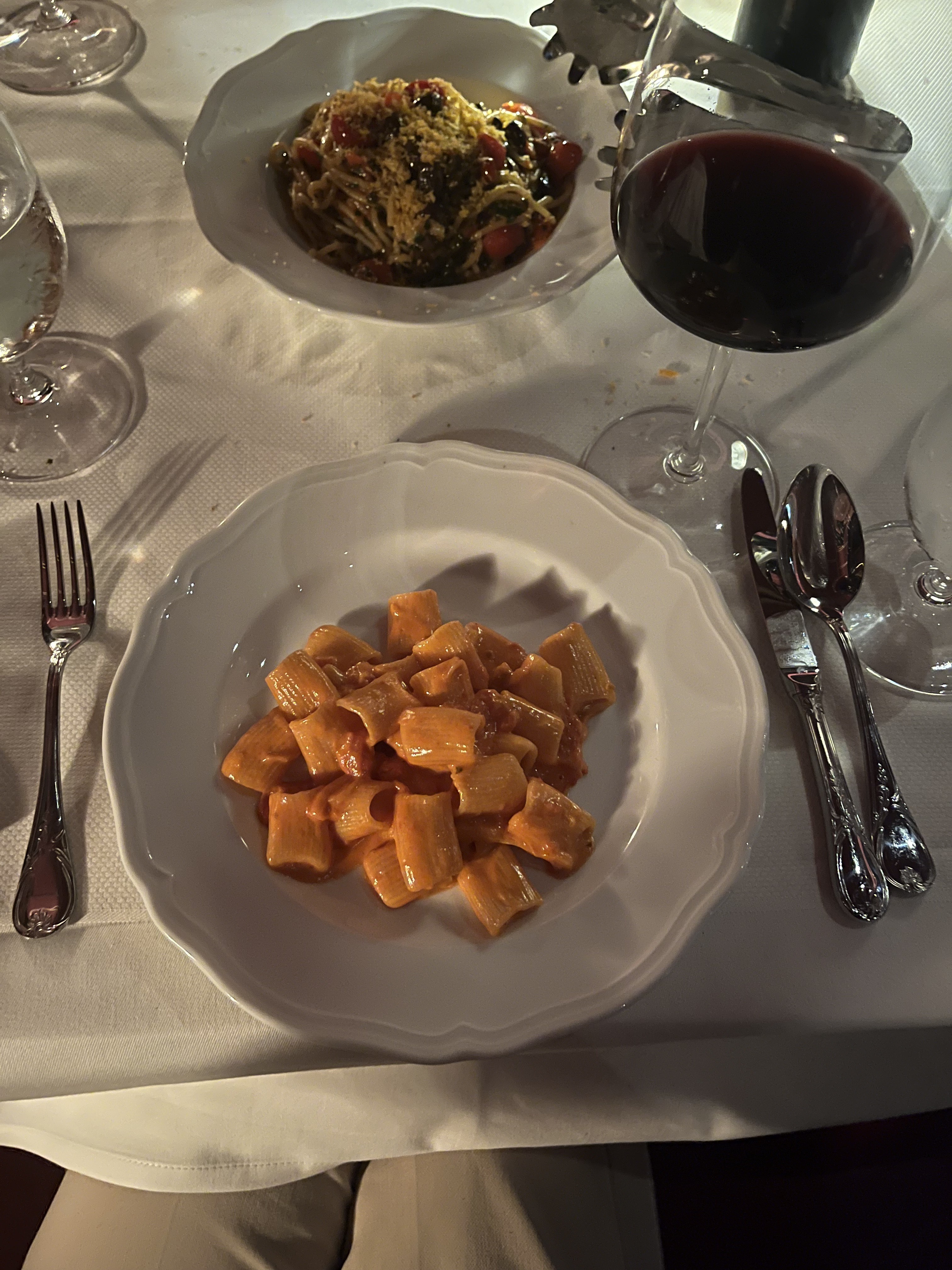 Pasta dishes and red wine at a restaurant table.