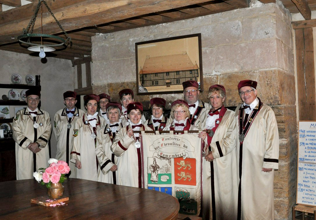 Members of the Confrérie des Chevaliers du Camembert holding their banner.