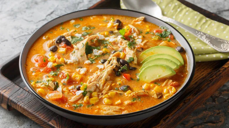 Closeup of chicken enchilada and black bean soup with avocado