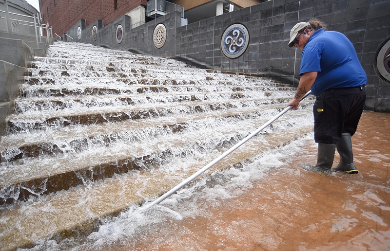 Staff photo by Matt Hamilton / On Sept. 2, 2025, Toby Quinton with the Tennessee Aquarium cleans algae patches from the Passage water feature in downtown Chattanooga. The water feature runs through September.