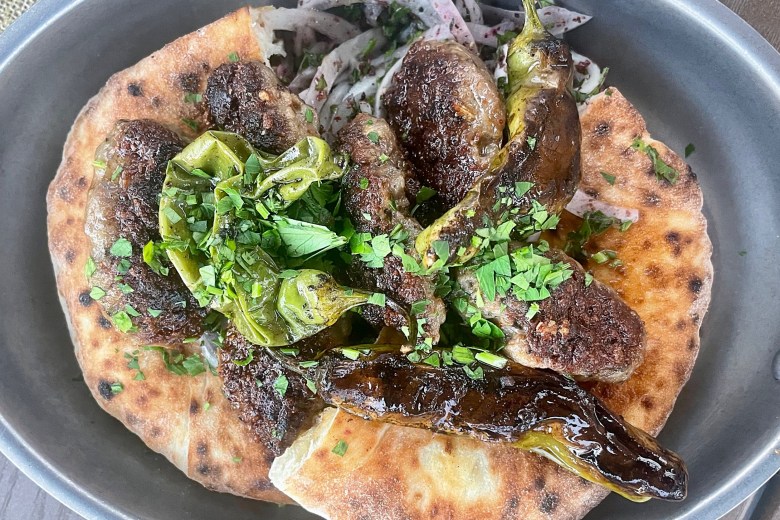 The Crispy Wagyu Meatballs feature lamb belly,pita, blistered shishitos,sumac,onions and tzatziki with soy butter and parsley.
