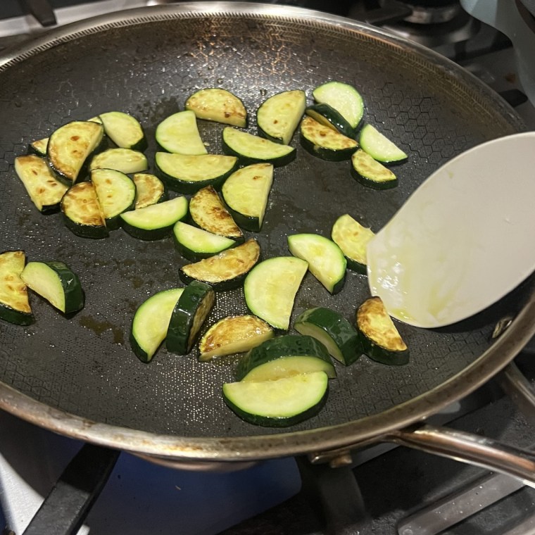 Sautéed zucchini in HexClad’s Hybrid Nonstick Frying Pan over a gas stove.