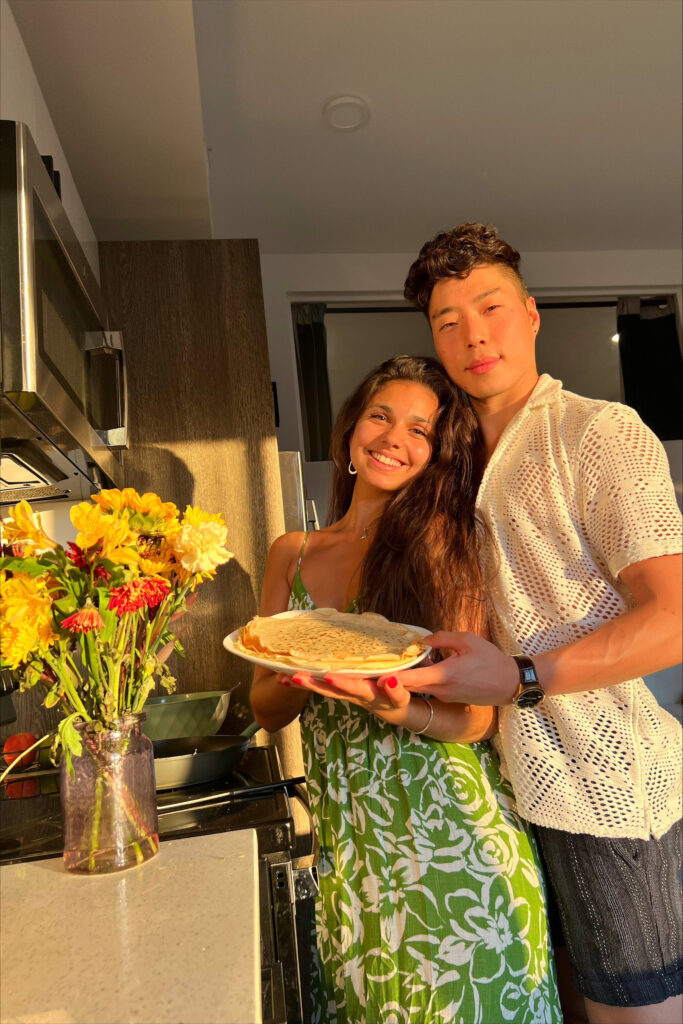 A couple holding a plate of crepes in the kitchen