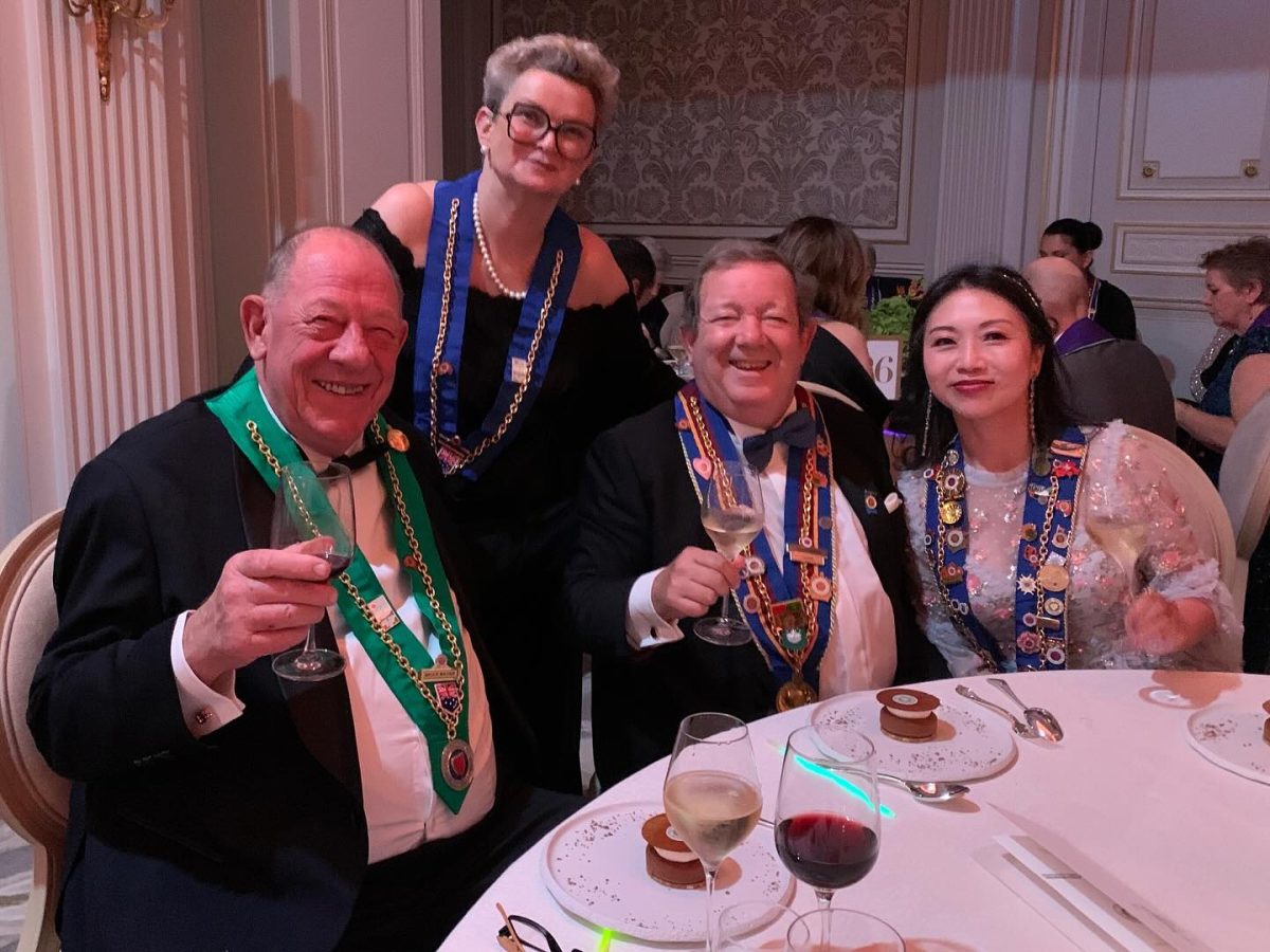 A group photo of four people wearing ribbons and medallions at a dinner table. 