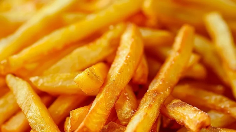 A close-up of salted, crispy French fries in a large pile