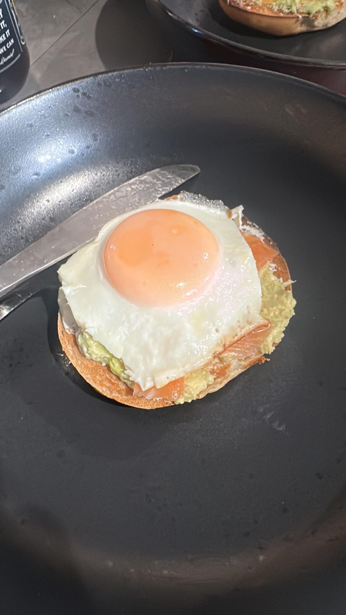 Salmon & cream cheese bagel with an egg on top of it